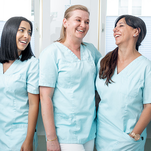 Drei lachende Mitarbeiterinnen in der Zahnarztpraxis Daniel Krutsch in Darmstadt.